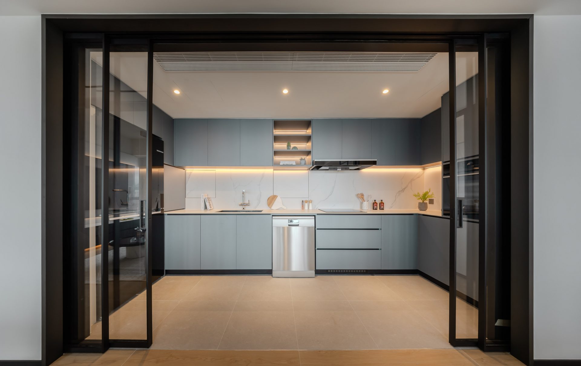 Double Cove — grey-green kitchen framed by black glazed sliding doors