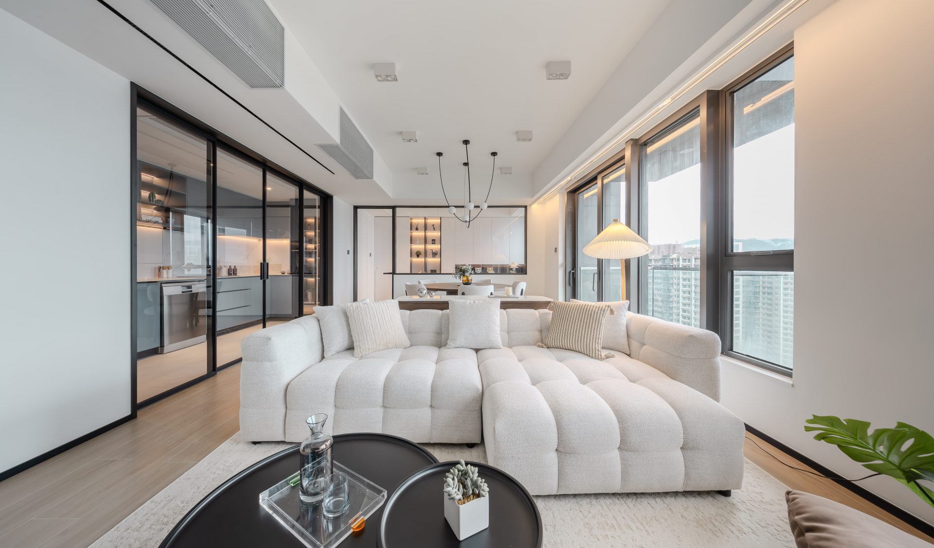 Double Cove — long living room connecting the dining area and black-framed glazed kitchen