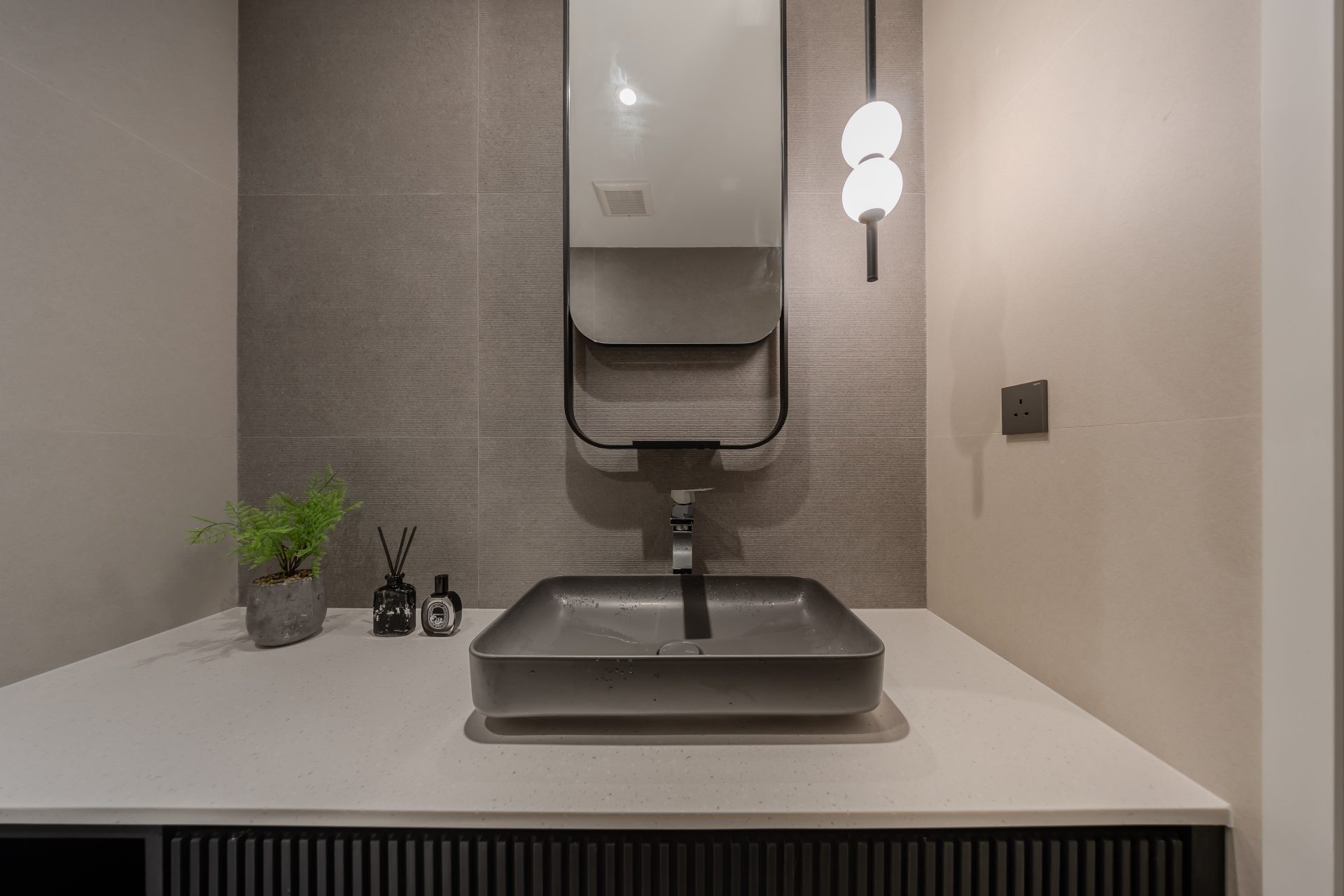 Double Cove — vanity with a ribbed dark cabinet, countertop basin and wall light