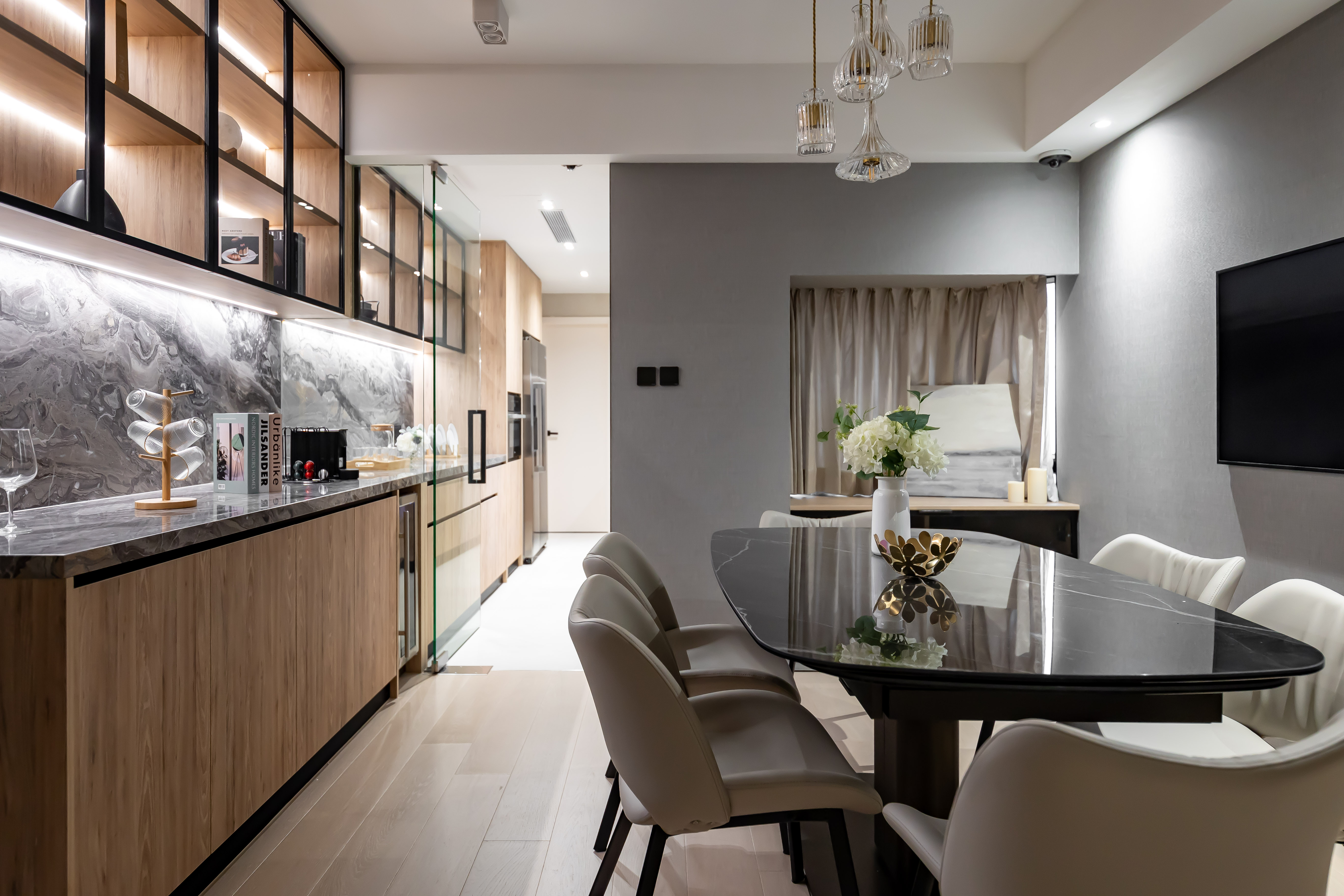 Modern dining room featuring a black marble-patterned oval table, grey chairs, and wooden cabinets with black metal-framed glass doors.