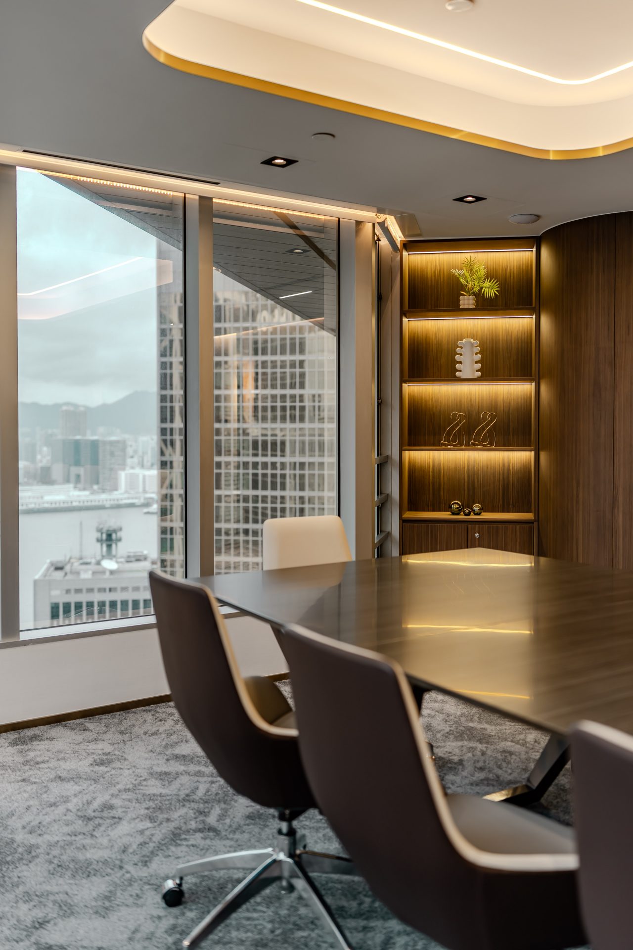 Han’s Laser Office — window-side meeting room with a dark timber display cabinet, conference table and gold lighting detail