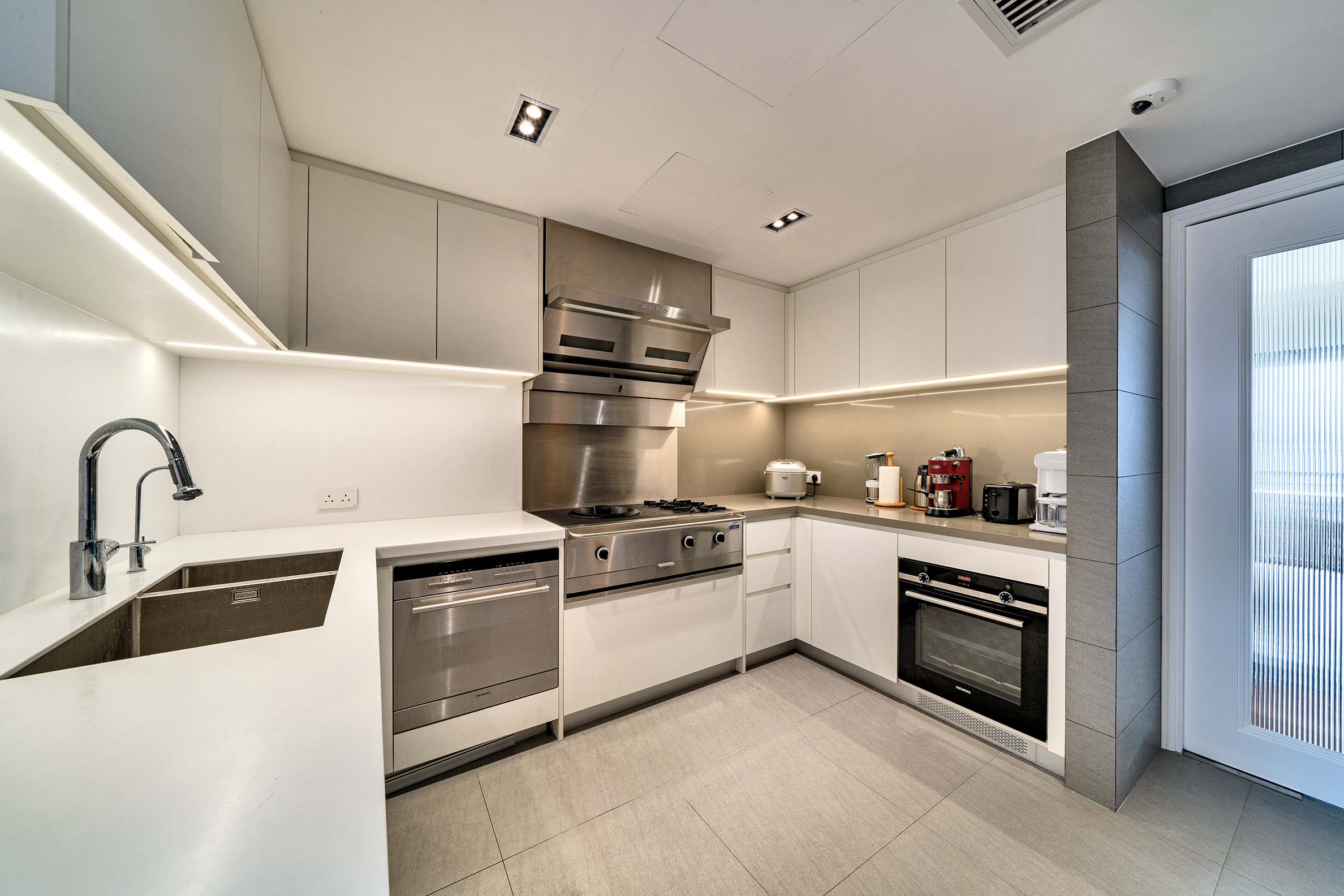Modern kitchen with white cabinets, stainless steel appliances, and a built-in oven.