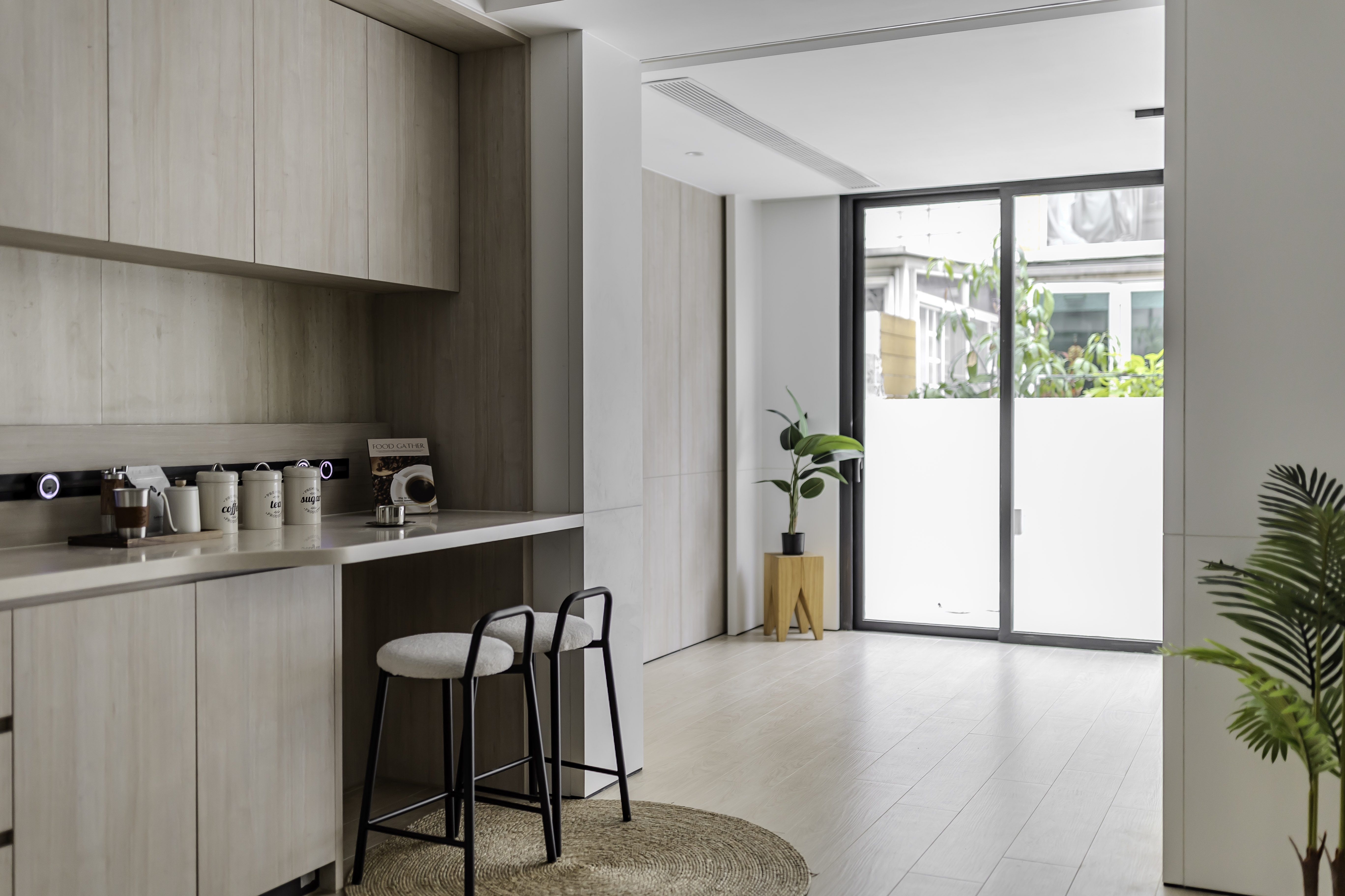 Interior space featuring a light wood bar counter with two high stools, light wood flooring, and a glass sliding door.