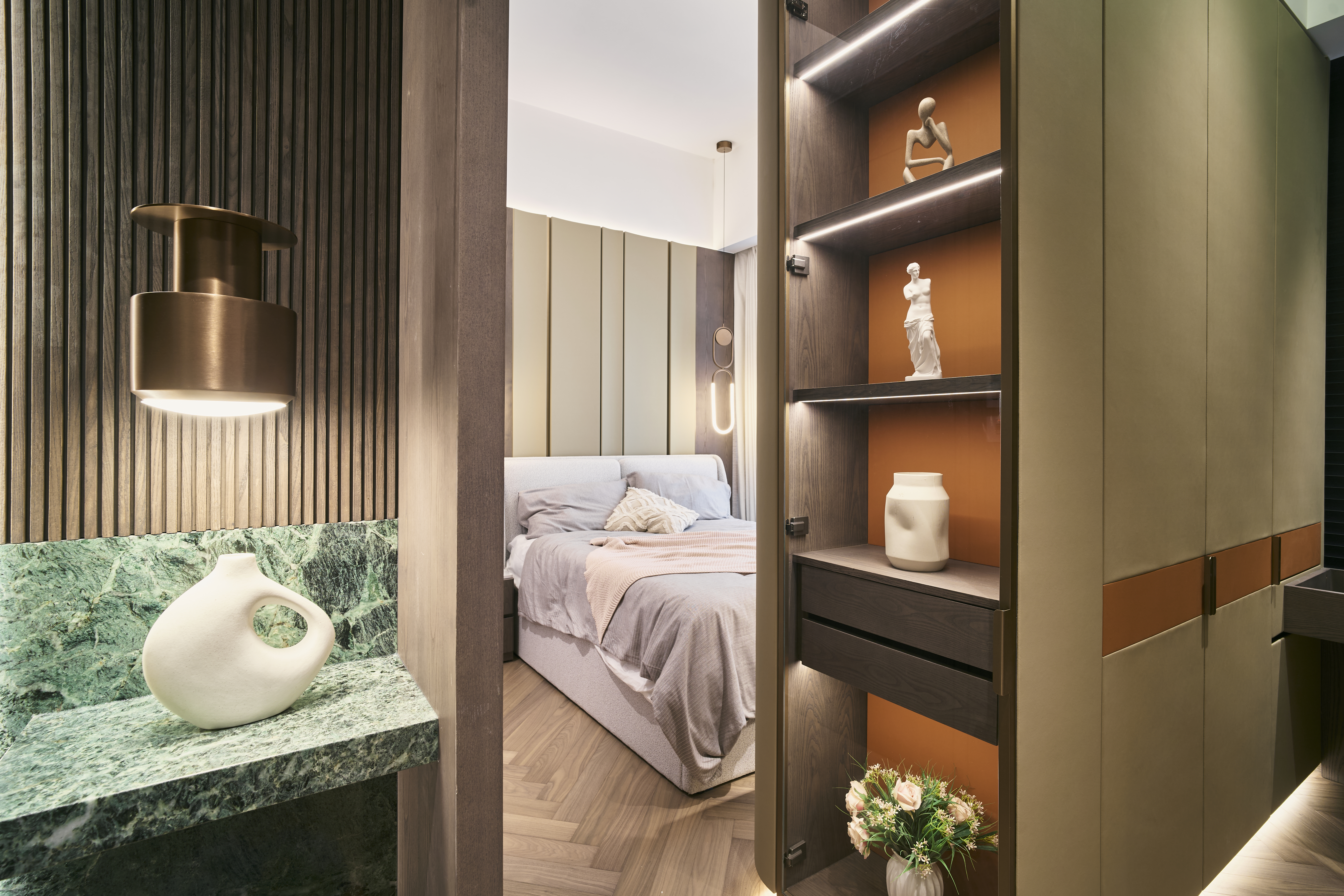 View into a bedroom showing a green marble counter, a white vase, and a glass display cabinet with orange backing.